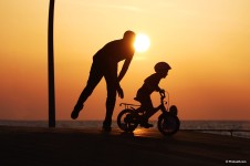 dad pushing son at sunset